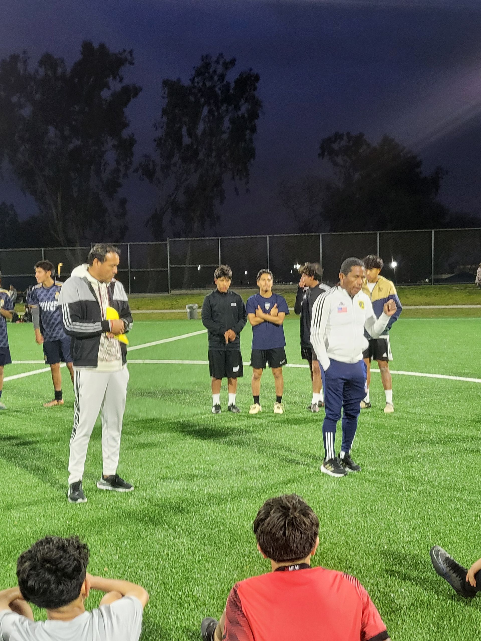 A group of people are standing on a soccer field at night - Santa Ana, CA - Mesa Verde Youth Soccer League 
