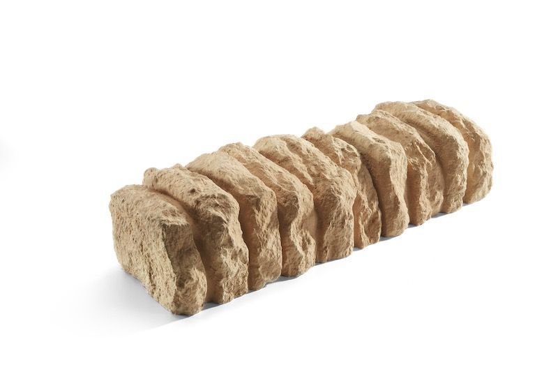 Tan, rectangular decorative garden border made of stacked, textured stone blocks.