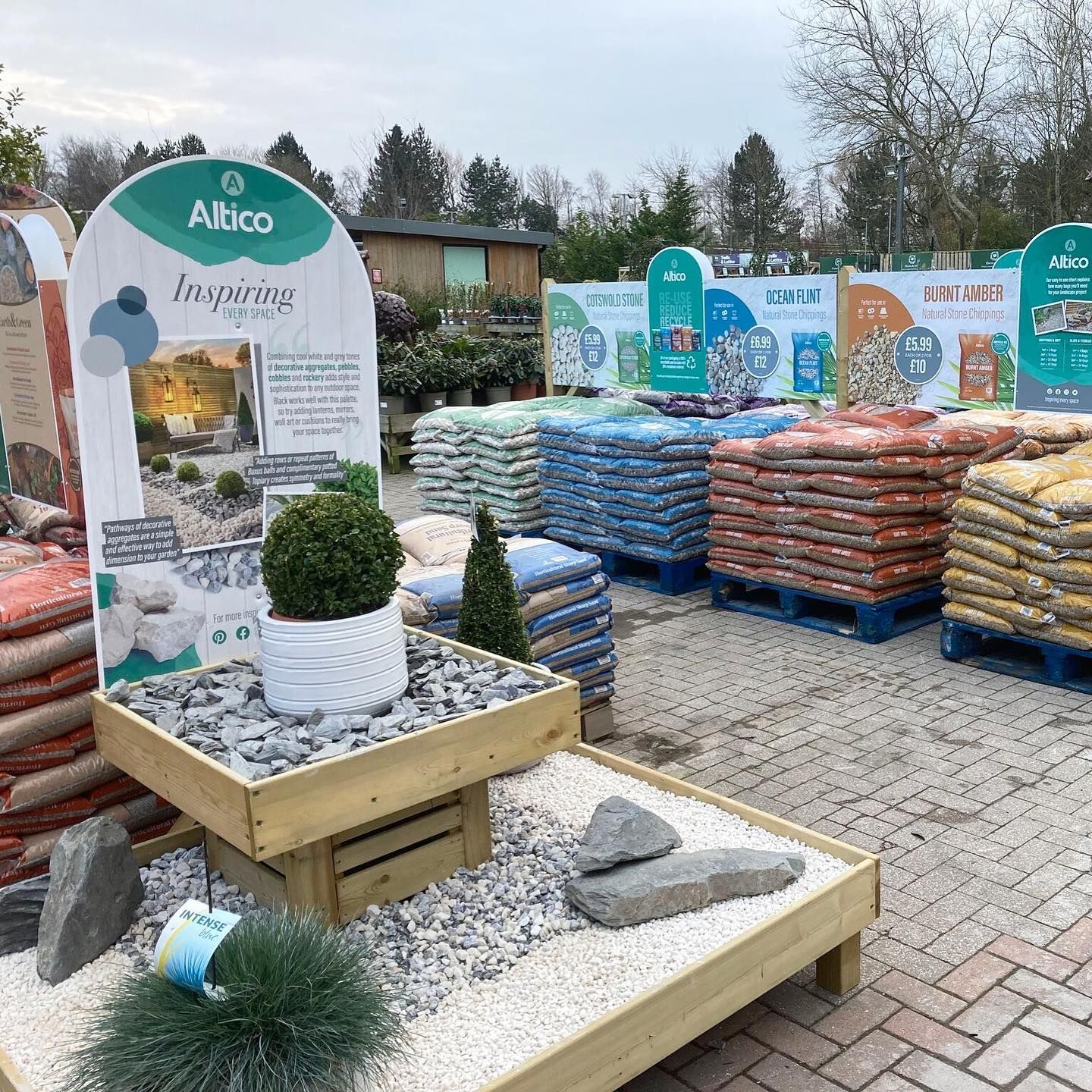 Display of landscaping supplies, including decorative rocks and soil bags, in an outdoor retail setting.