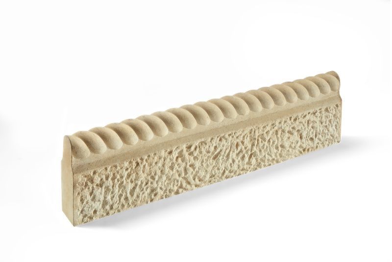 Beige stone molding with a textured surface and decorative top edge.