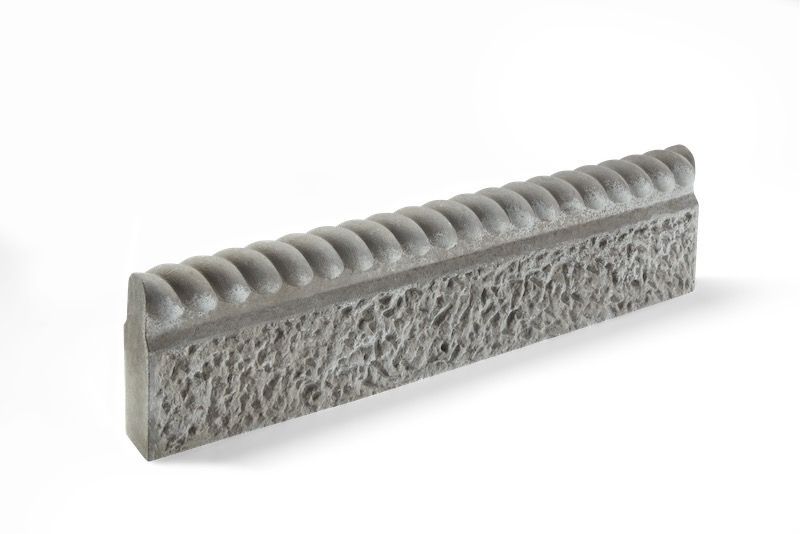 Gray concrete edging with a textured face and decorative top.