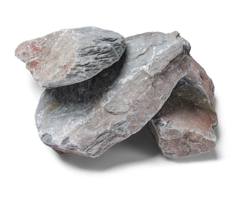 Pile of gray and reddish-brown stones with rough, layered texture on a white background.