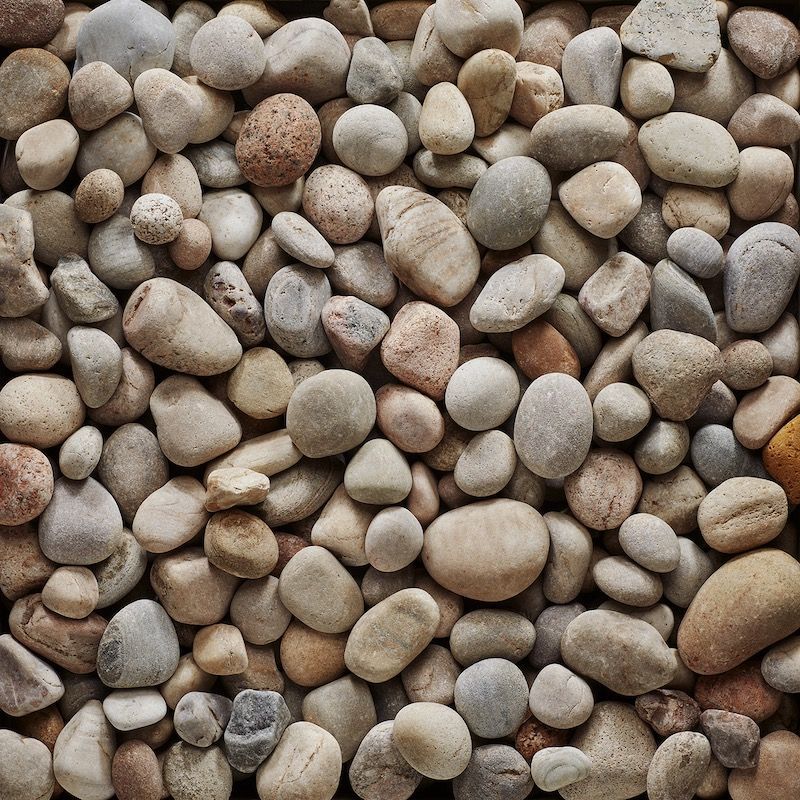 Close-up of a pile of smooth, rounded river rocks in shades of tan, gray, and brown.