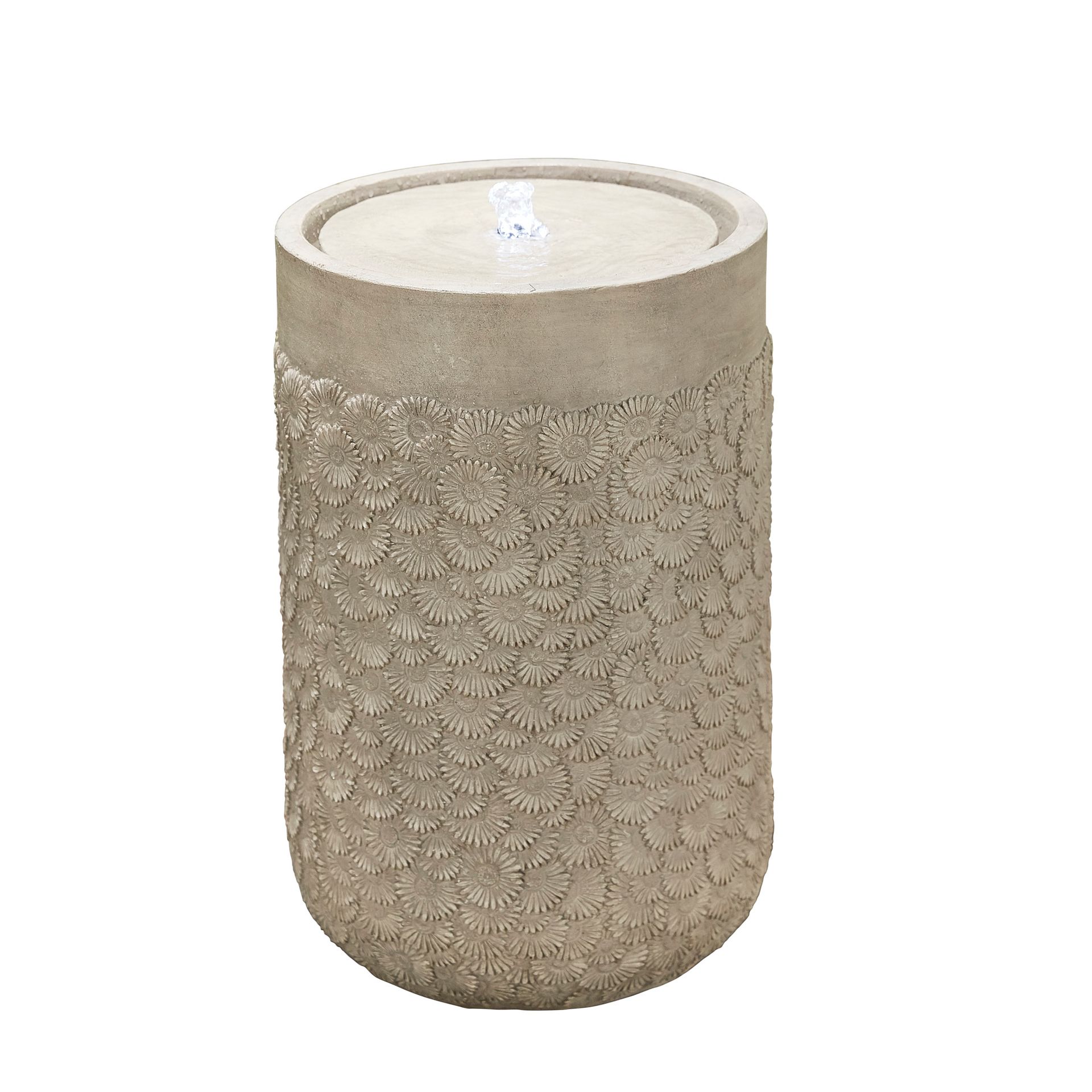 Cylindrical outdoor fountain with textured surface, light gray concrete. Water trickles from the top.