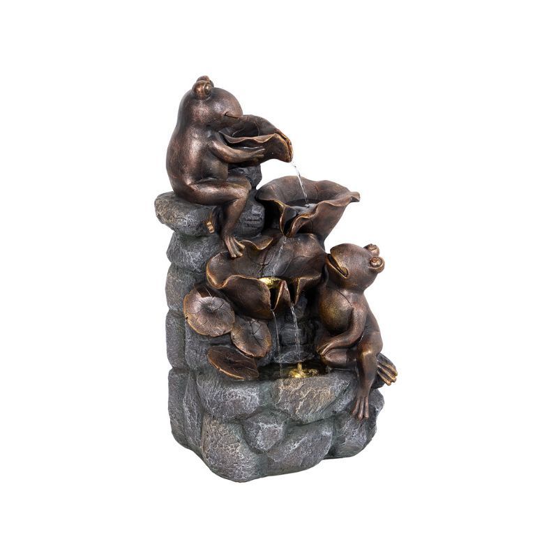 Bronze frog fountain with water cascading from lily pads, set on a stone structure.