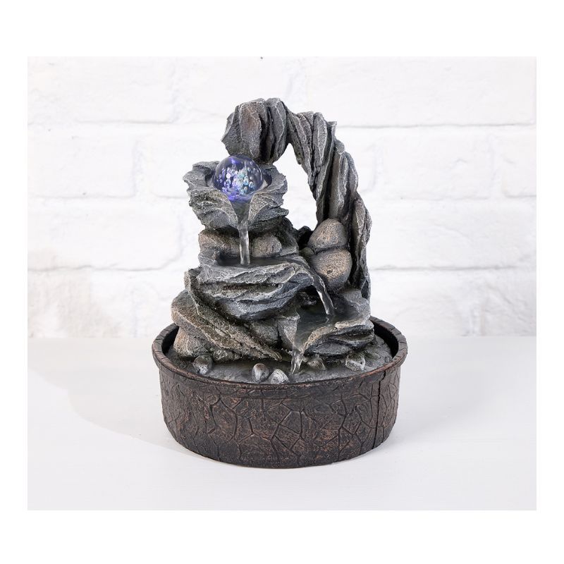 Indoor water fountain with a rock and arched design; water flowing from the top.