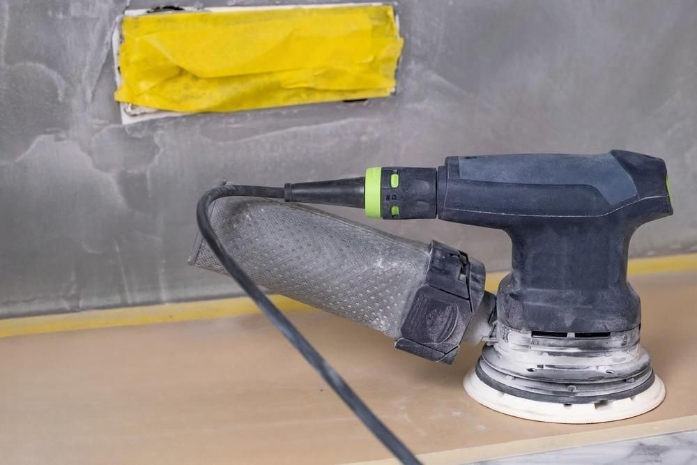 A sander is sitting on top of a wooden table.