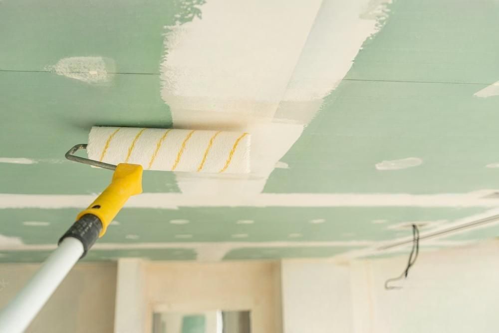 A person is painting a ceiling with a paint roller.