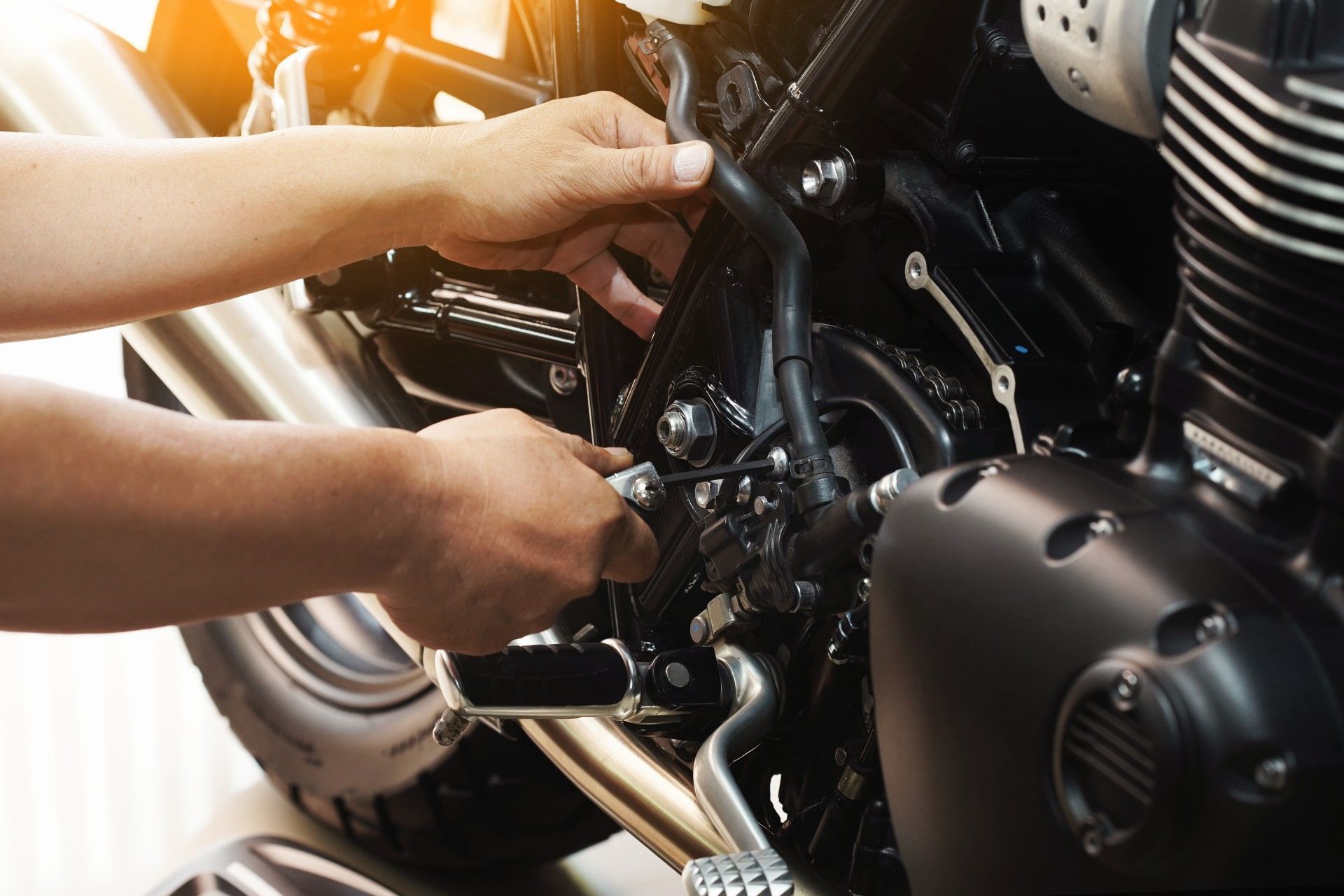 A person is working on a motorcycle with a wrench.