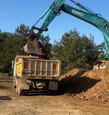 A Kobelco Excavator Is Loading Dirt Into A Dump Truck — GCE Earthworks Pty Ltd In Krambach, NSW