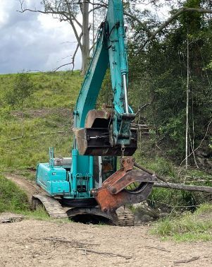 A Large Excavator Is Sitting On Top Of A Dirt Field — GCE Earthworks Pty Ltd In Krambach, NSW