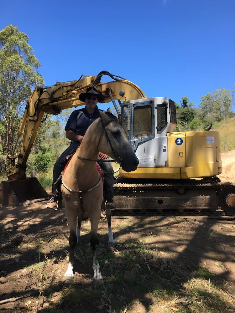 A Man Is Riding A Horse In Front Of A Bulldozer — GCE Earthworks Pty Ltd In Krambach, NSW