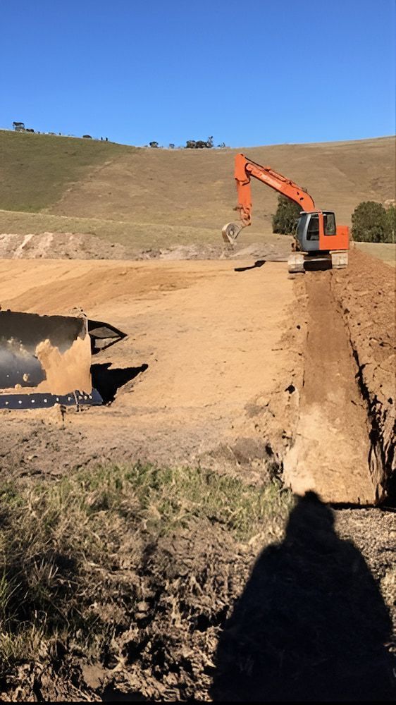 A Bulldozer Is Digging A Hole In The Dirt In A Field — GCE Earthworks Pty Ltd In Krambach, NSW