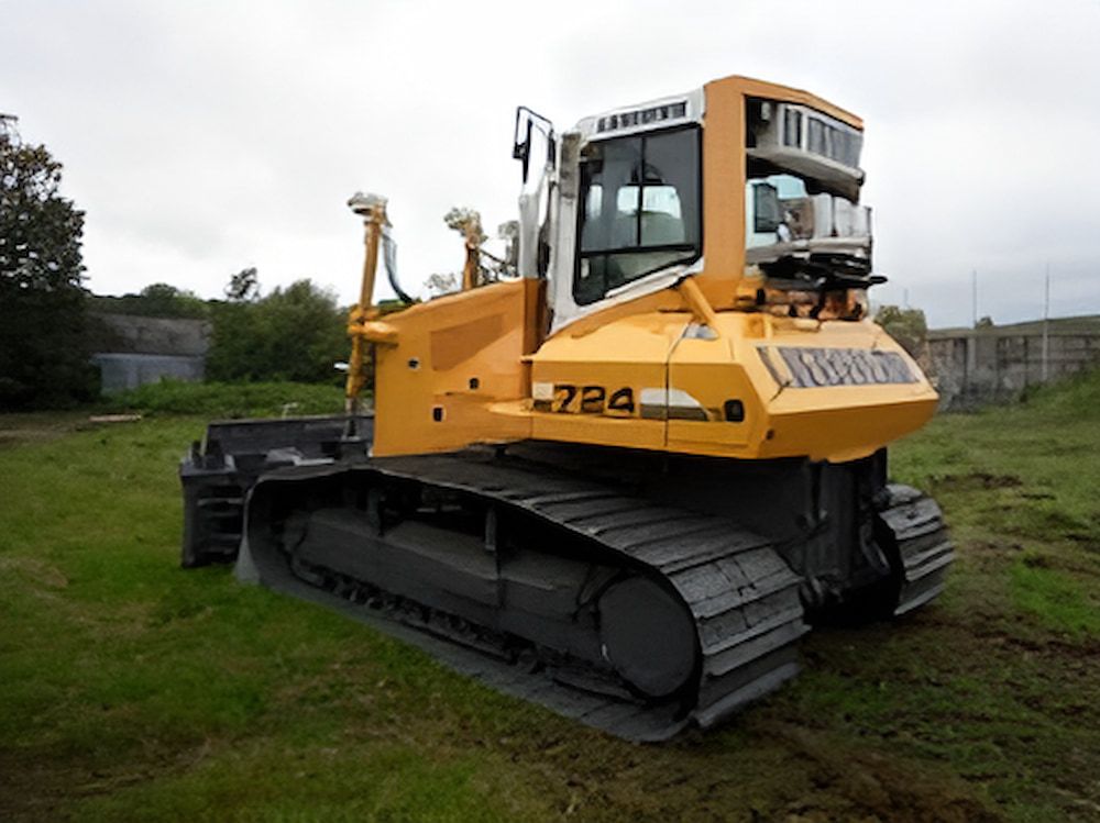 A Yellow And White Liebherr Bulldozer Is Parked In A Grassy Field — GCE Earthworks Pty Ltd In Krambach, NSW