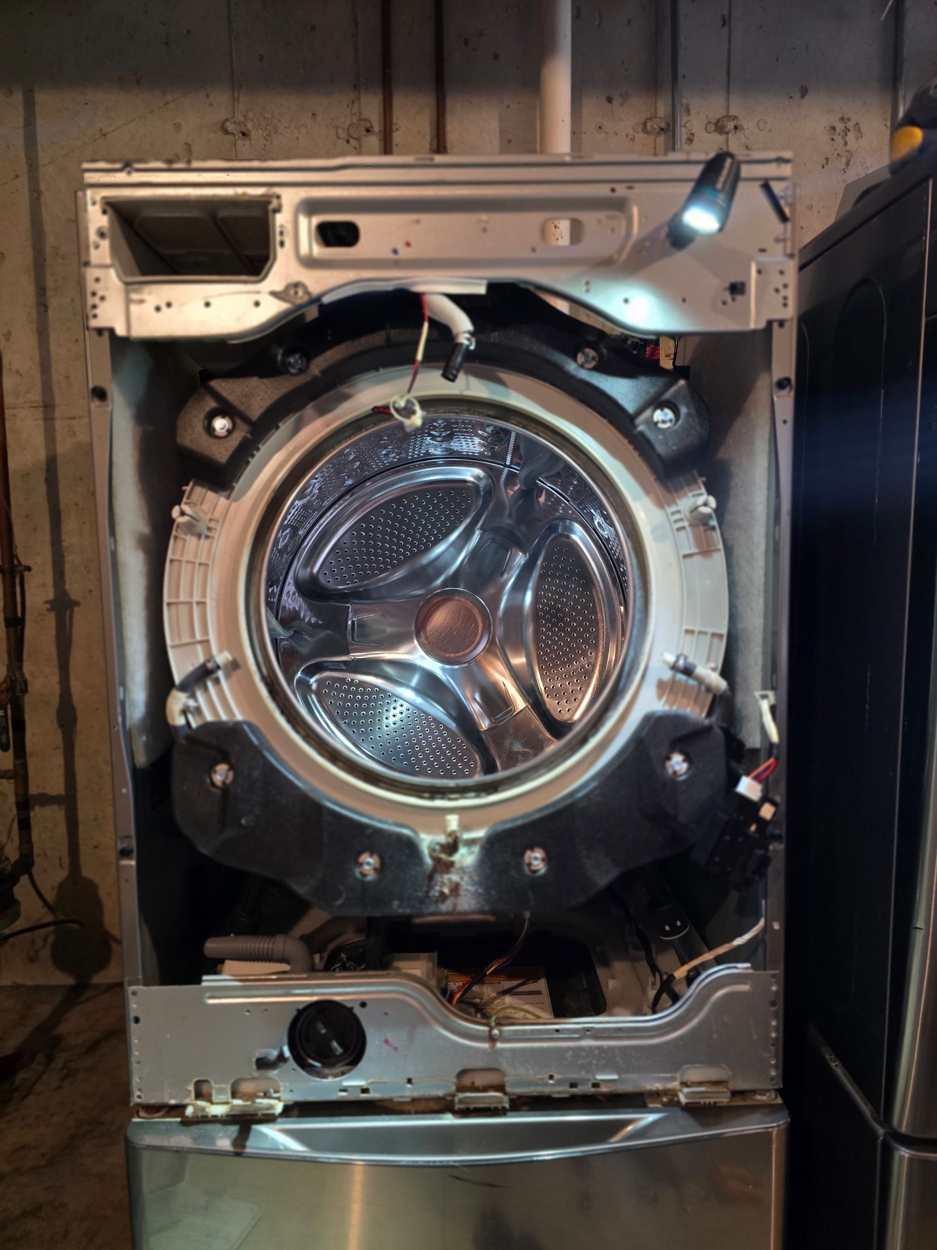Washing machine with front panel removed, showing the drum and internal components.