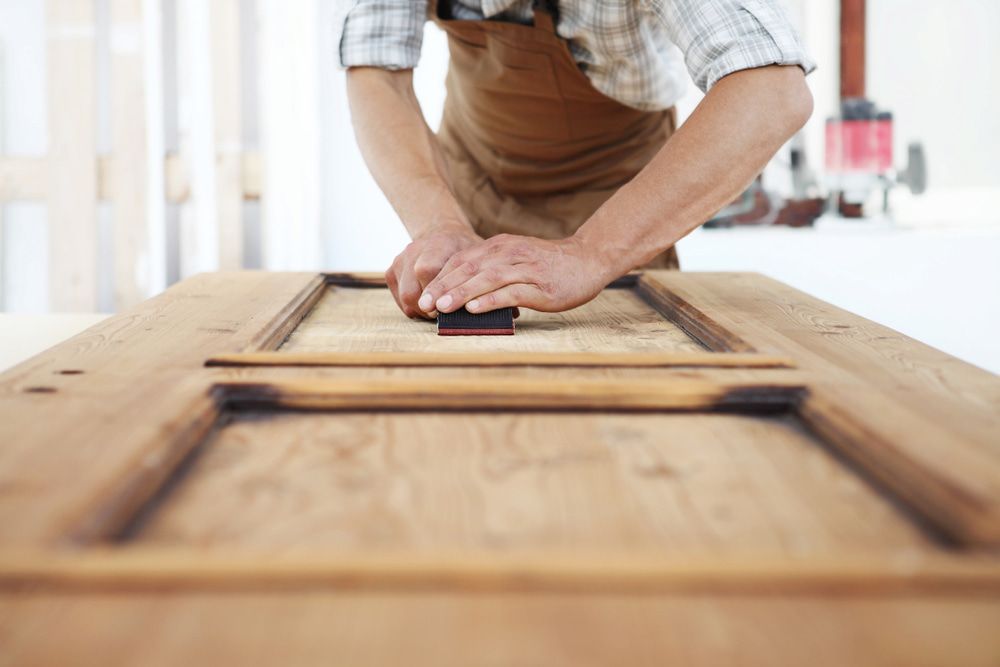 A Man Is Sanding A Piece Of Wood With A Sander — Johnson's Timber Agencies In Ulladulla, NSW