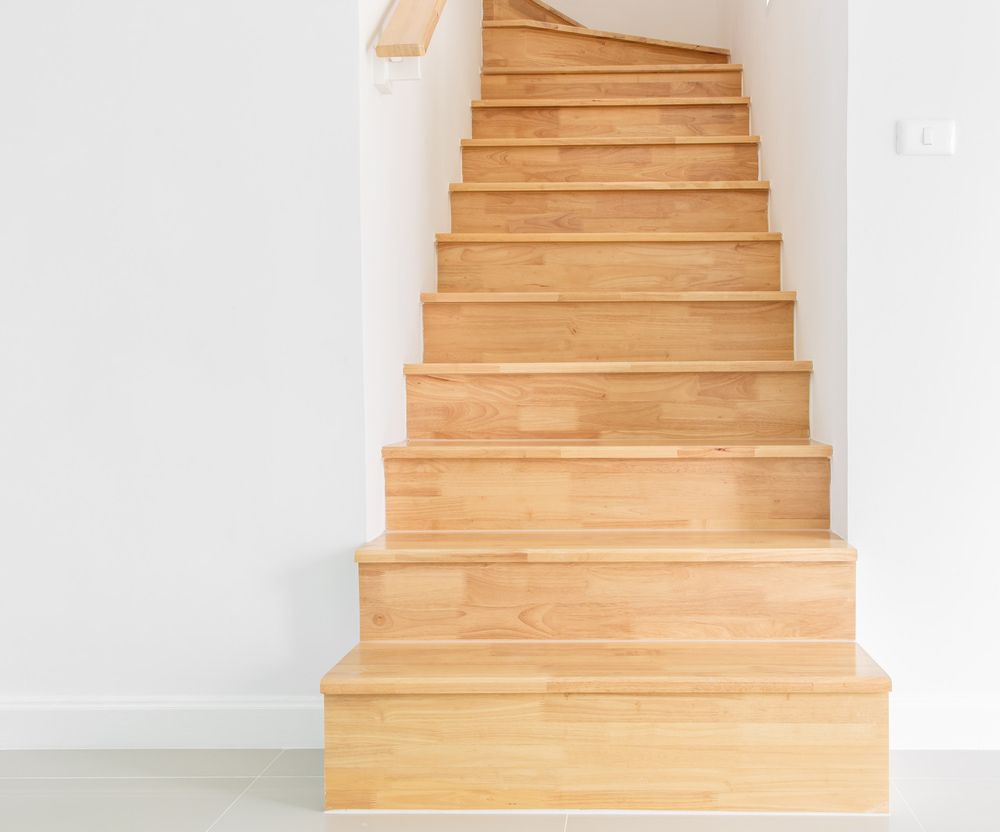 A Wooden Staircase In An Empty Room With A White Wall — Johnson's Timber Agencies In Ulladulla, NSW