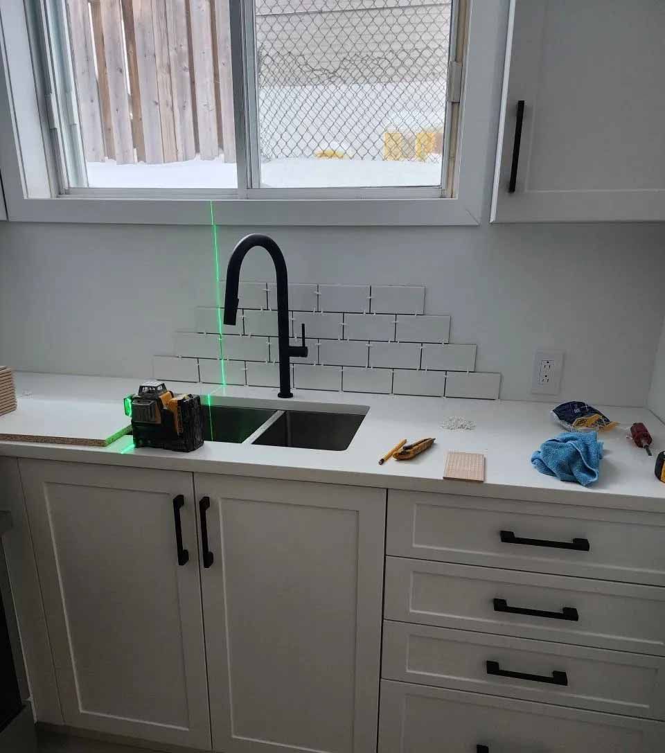 Cuisine blanche avec installation d'un nouvel évier, d'une crédence et de nouveaux placards.