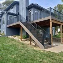 Exterior view of a house with a multi-level deck and stairs leading down to a green lawn.