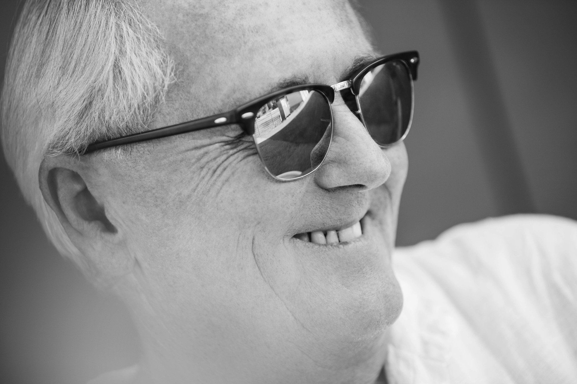 Auf einem Schwarzweißfoto lächelt ein Mann mit Sonnenbrille.