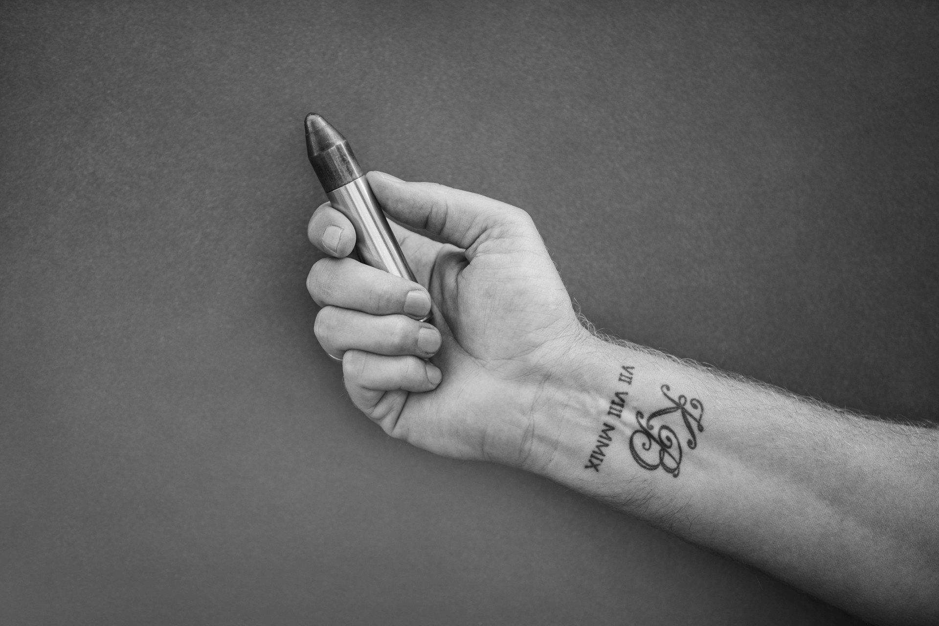 Eine Person mit einer Tätowierung am Handgelenk hält einen Stift.