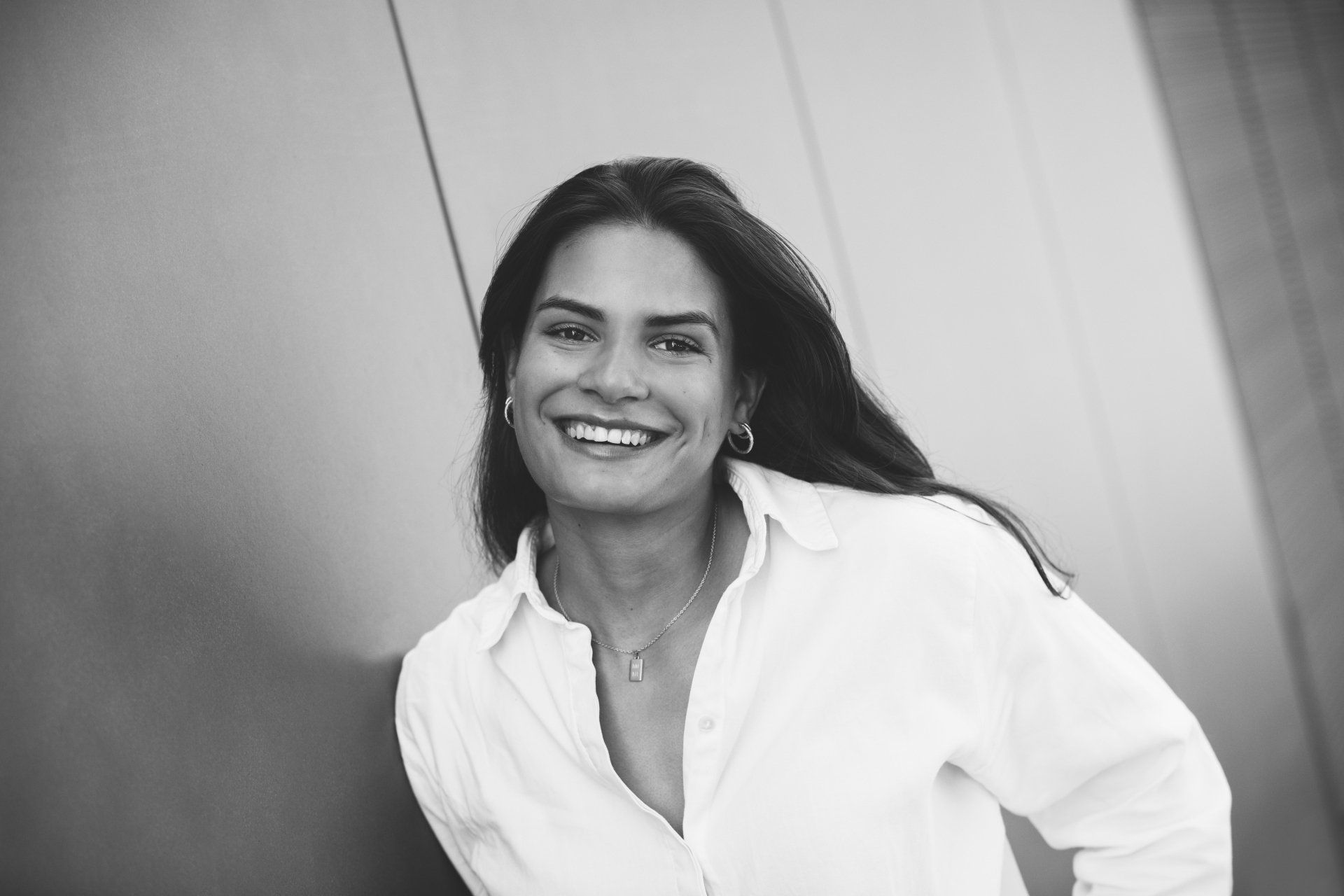 Auf einem Schwarzweißfoto lächelt eine Frau in einem weißen Hemd.