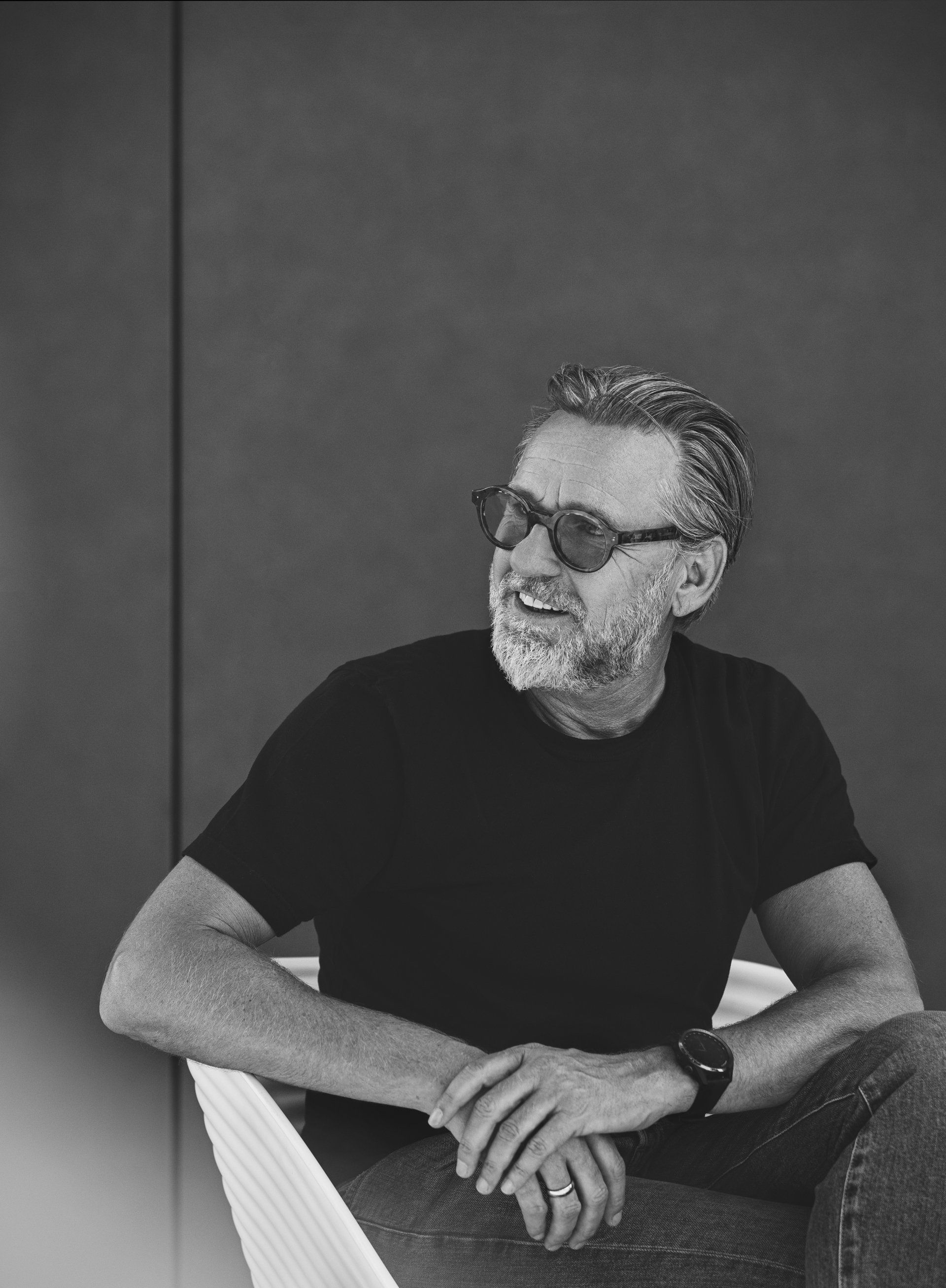 Ein Schwarzweißfoto eines Mannes mit Sonnenbrille und schwarzem Hemd.