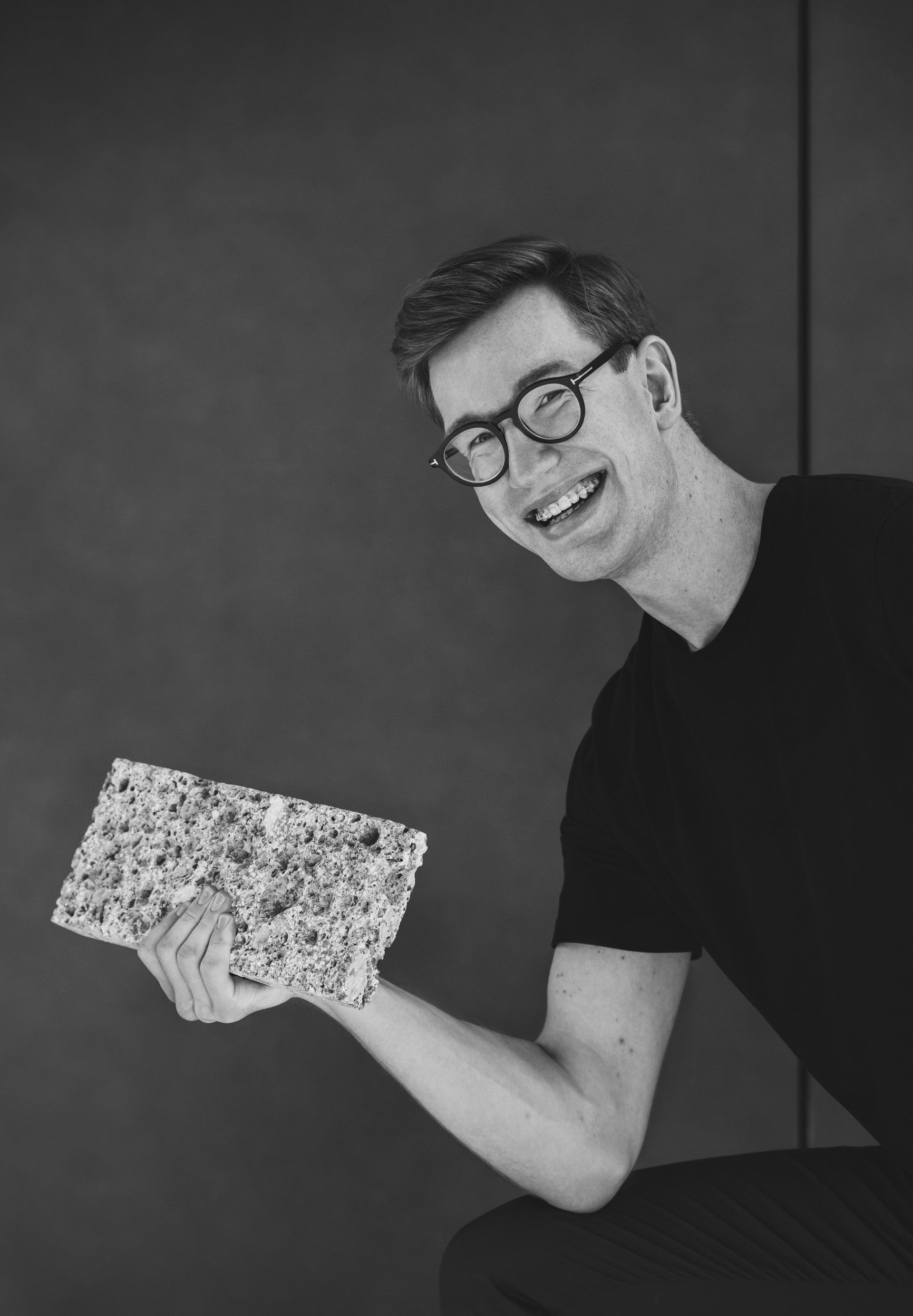 Ein Mann mit Brille hält ein Stück Essen in der Hand.