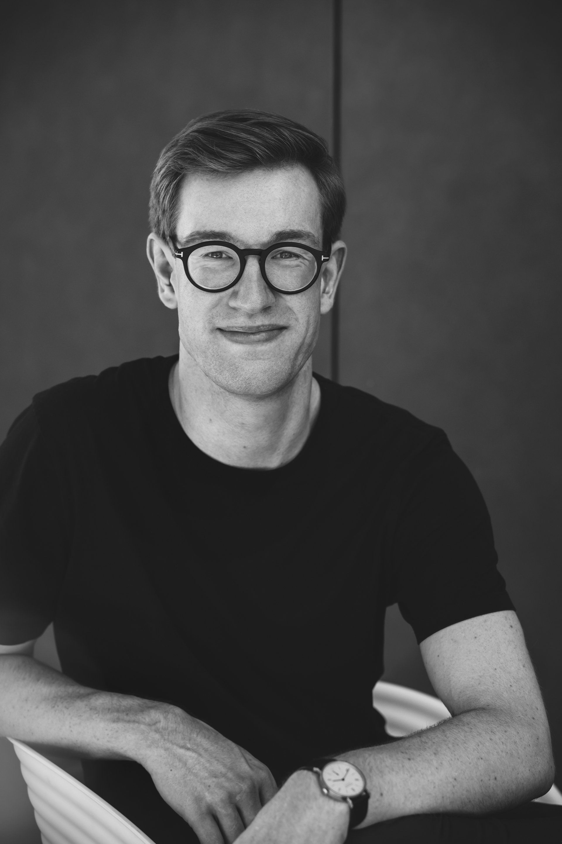 Ein Schwarzweißfoto eines Mannes mit Brille und Uhr.