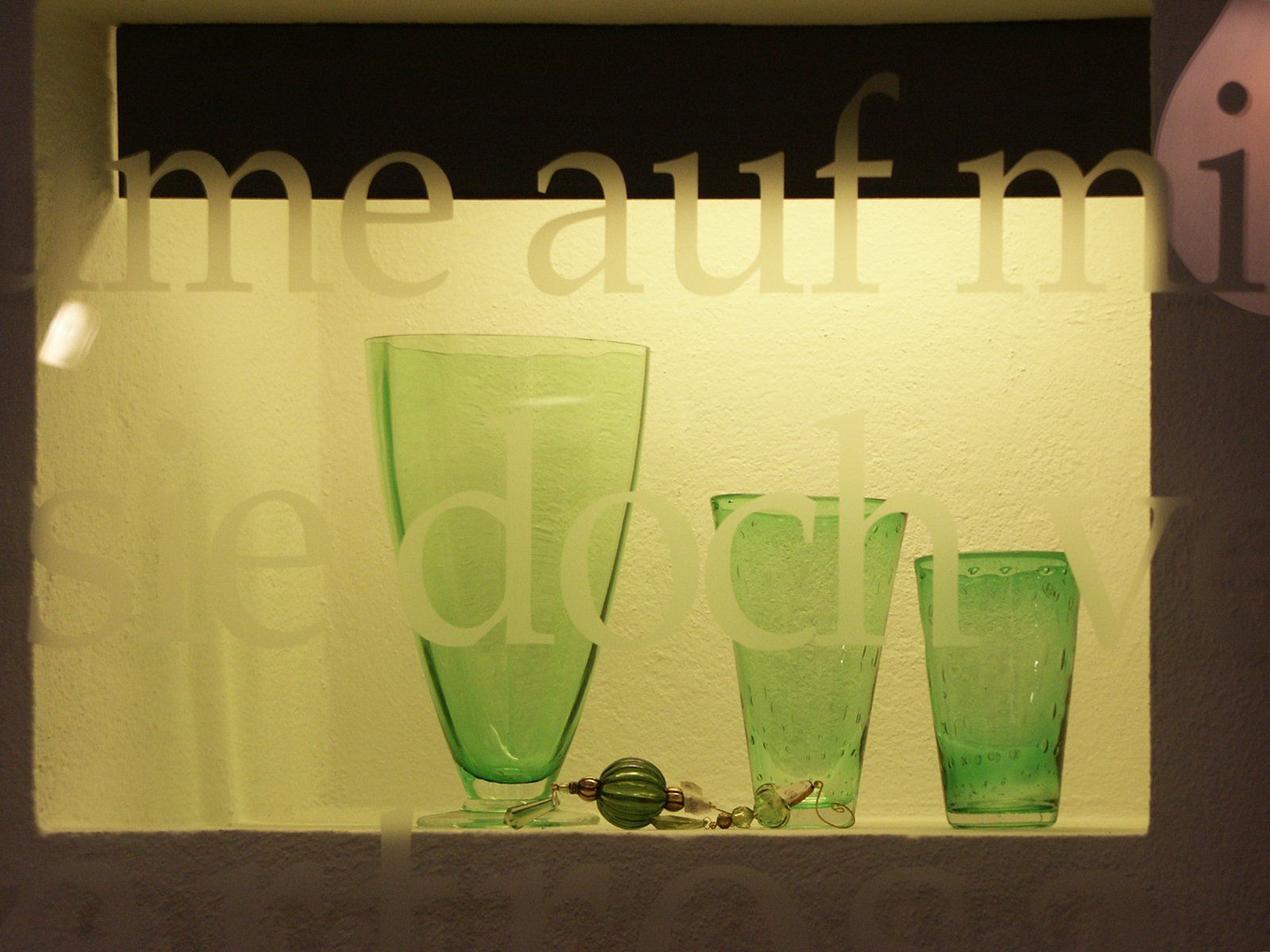 Zwei grüne Gläser sitzen auf einem Regal vor einem Schild mit der Aufschrift „Me auf m“