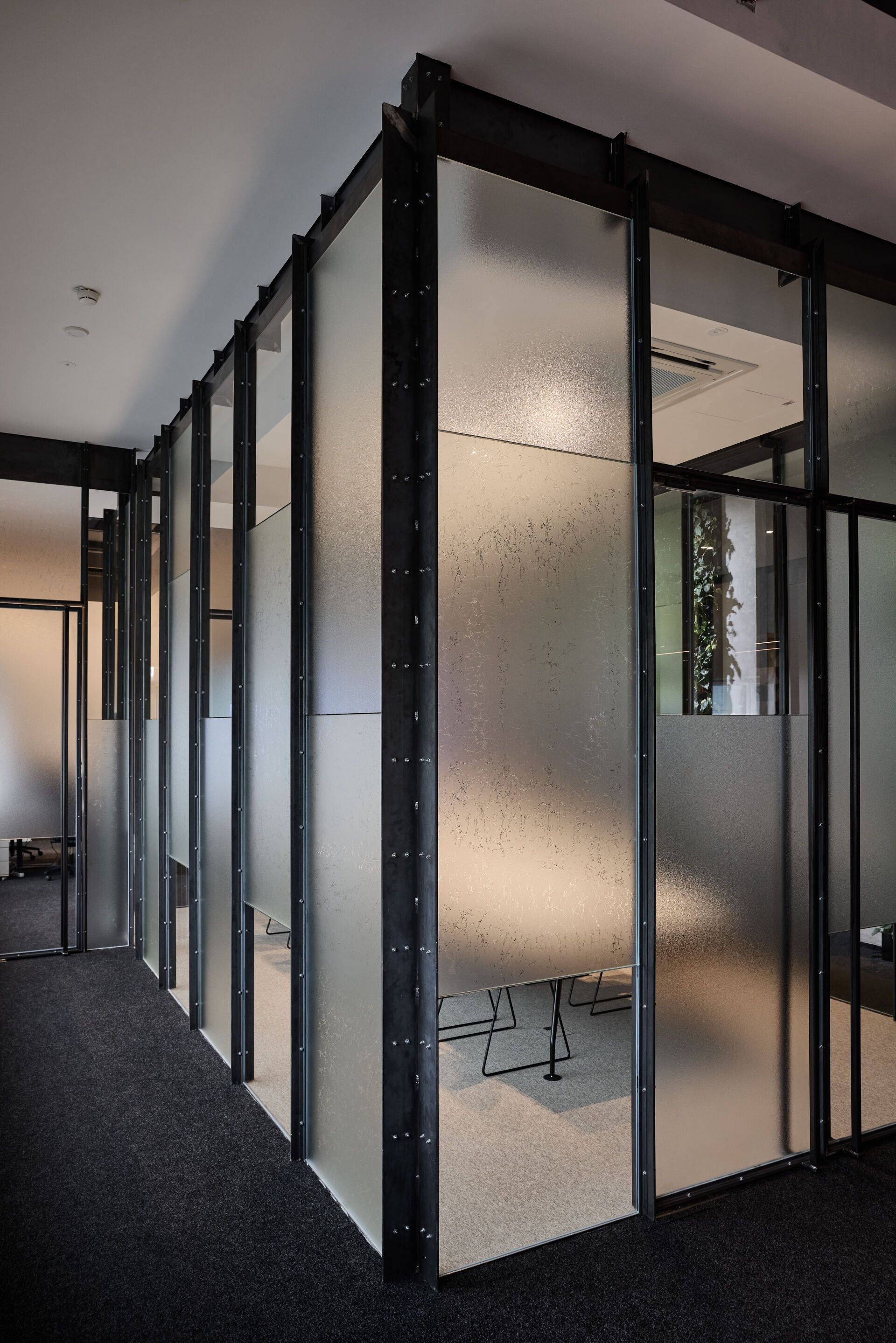 Ein Flur mit einer Reihe Glaswänden und einem schwarzen Teppich