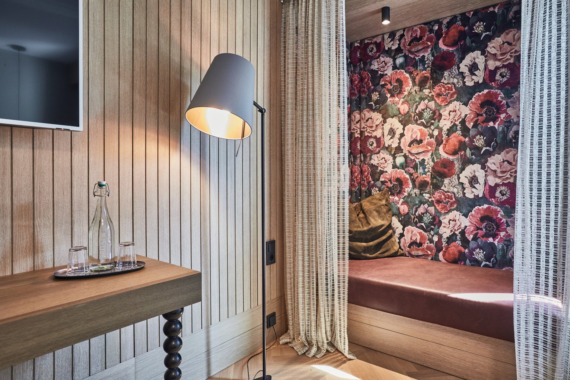 Ein Zimmer mit einer Blumentapete und einer Lampe