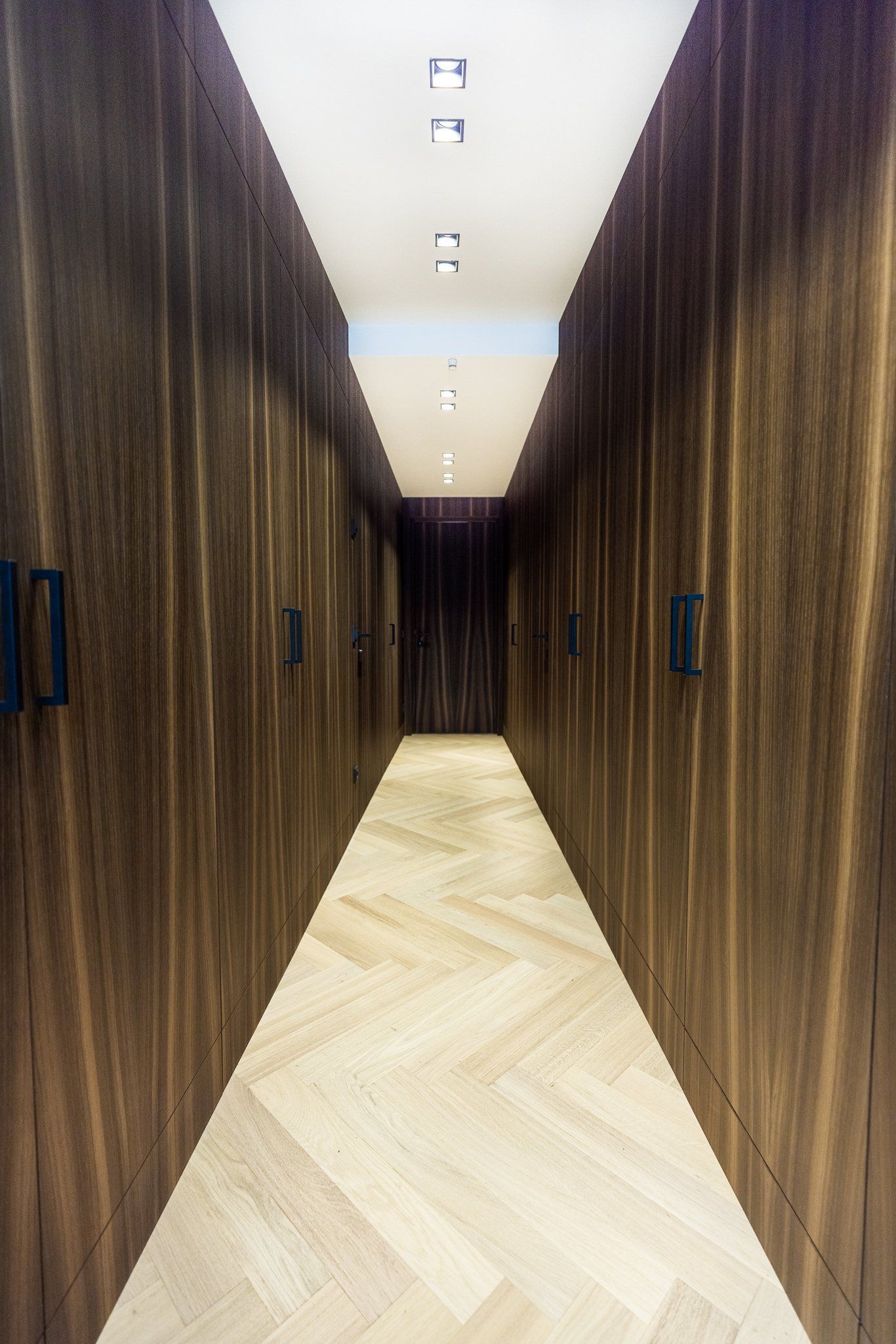 Ein langer Flur mit Holzwänden und Fischgrätboden