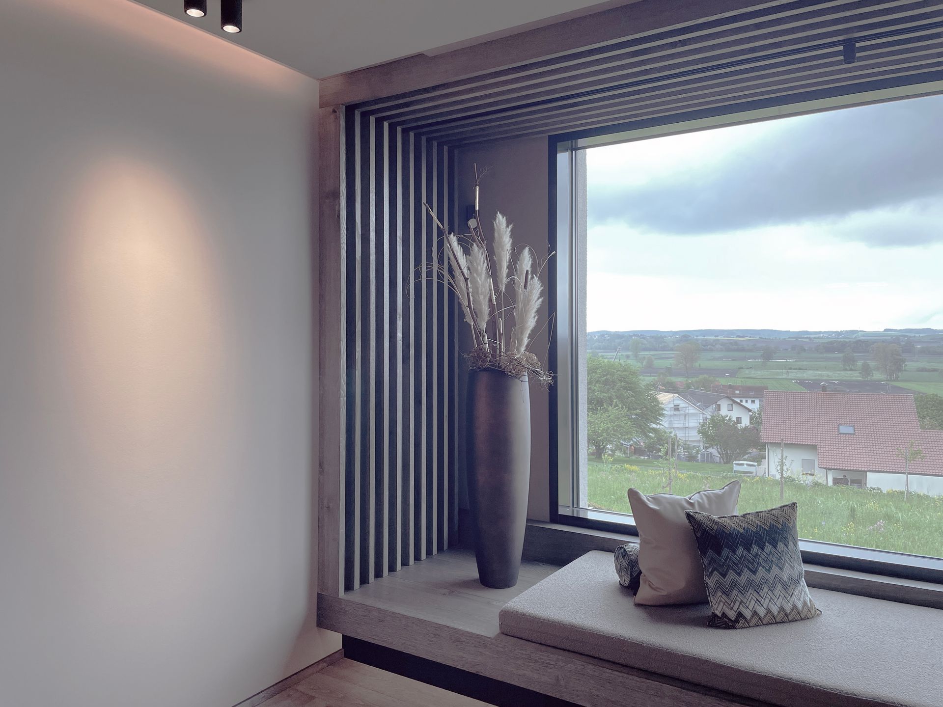 Ein Zimmer mit einem Fenster und einer Vase mit Blumen auf der Fensterbank