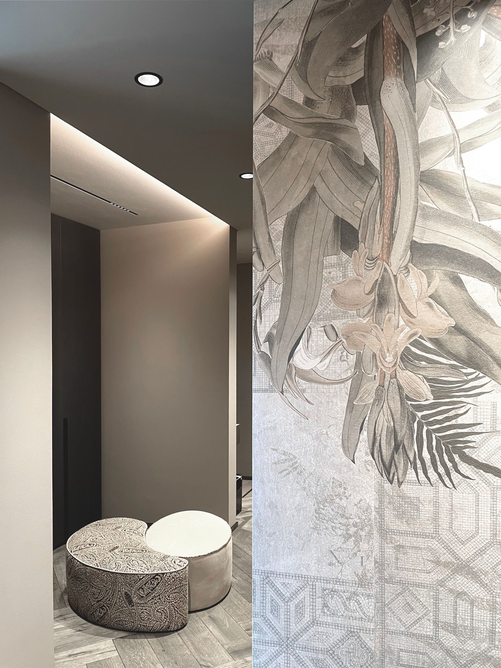 Ein Flur mit zwei Ottomanen und einem großen Gemälde an der Wand.