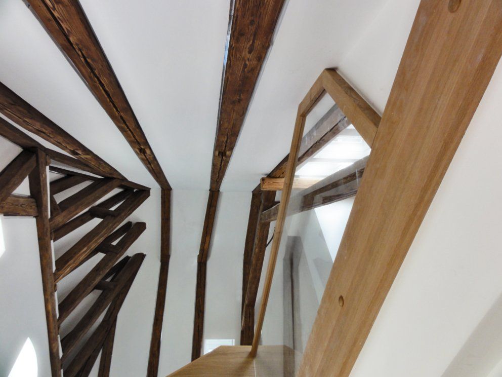 Blick nach oben auf eine Holztreppe mit Glasgeländer