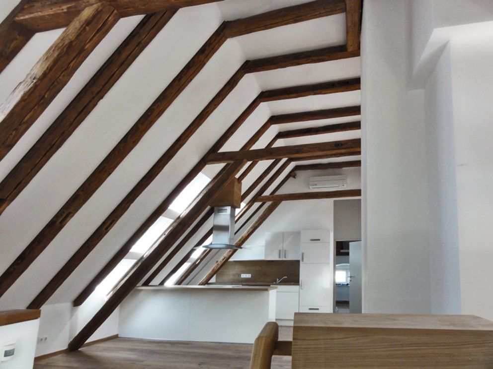 Eine Küche im Dachgeschoss mit Holzbalken und weißen Wänden