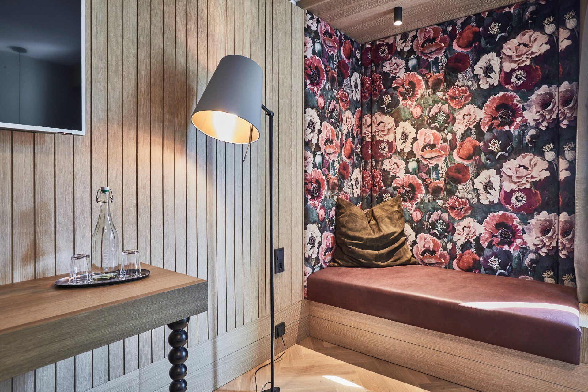 Ein Zimmer mit einer Blumentapete und einer Lampe