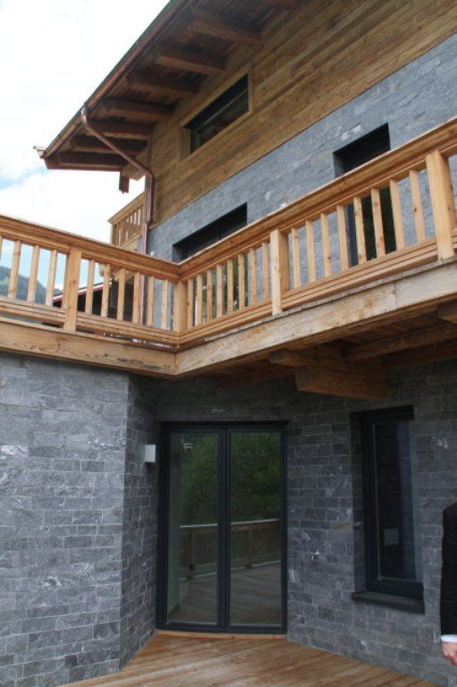 Ein Mann steht vor einem Haus mit einem Holzbalkon