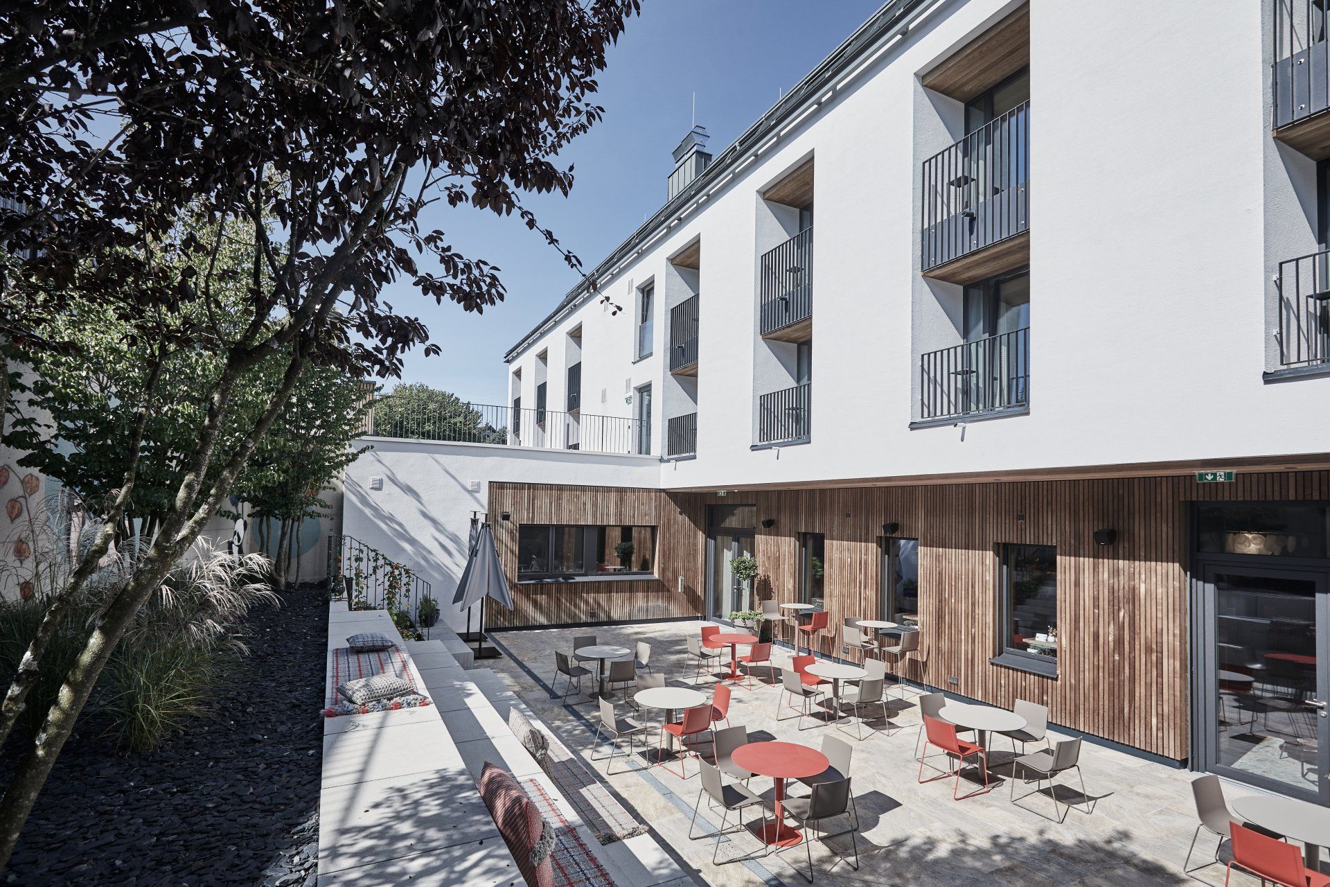 Ein großes Gebäude mit einer Terrasse mit Tischen und Stühlen davor