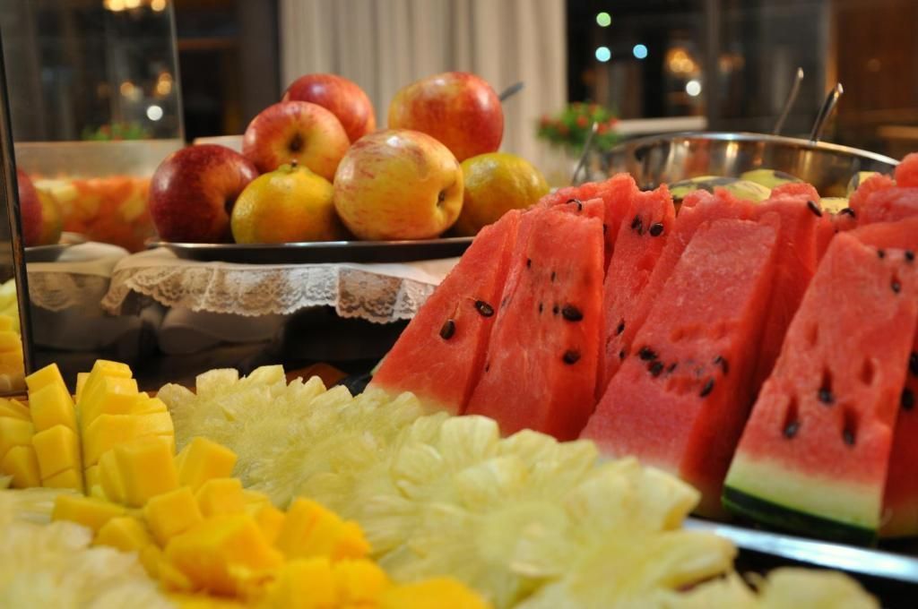 Uma mesa de buffet coberta com melancia, abacaxi e maçãs.