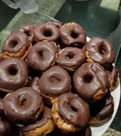 Um prato branco coberto com donuts com cobertura de chocolate sobre uma mesa.