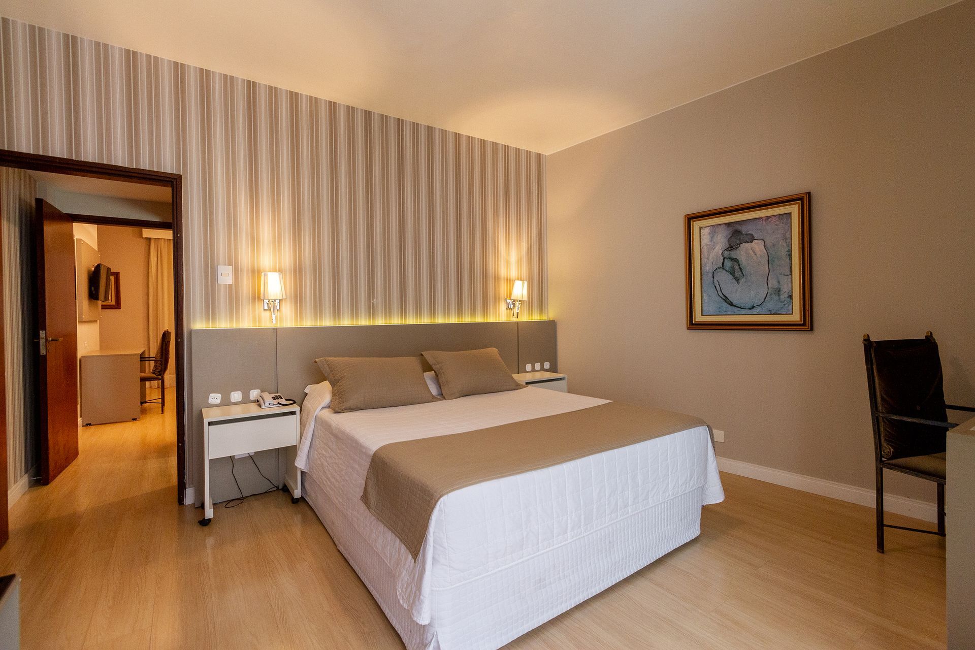 Um quarto de hotel com cama king size e uma cadeira.