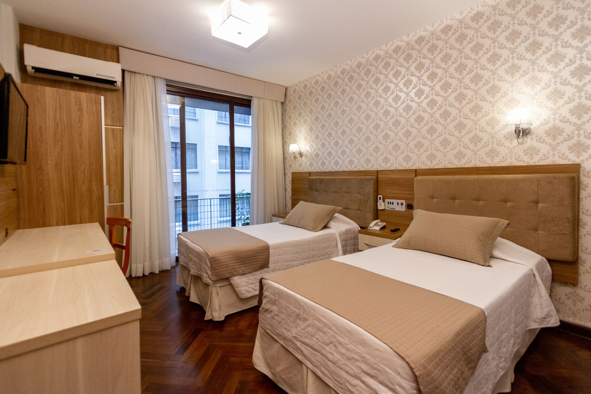 Um quarto de hotel com duas camas e uma televisão.