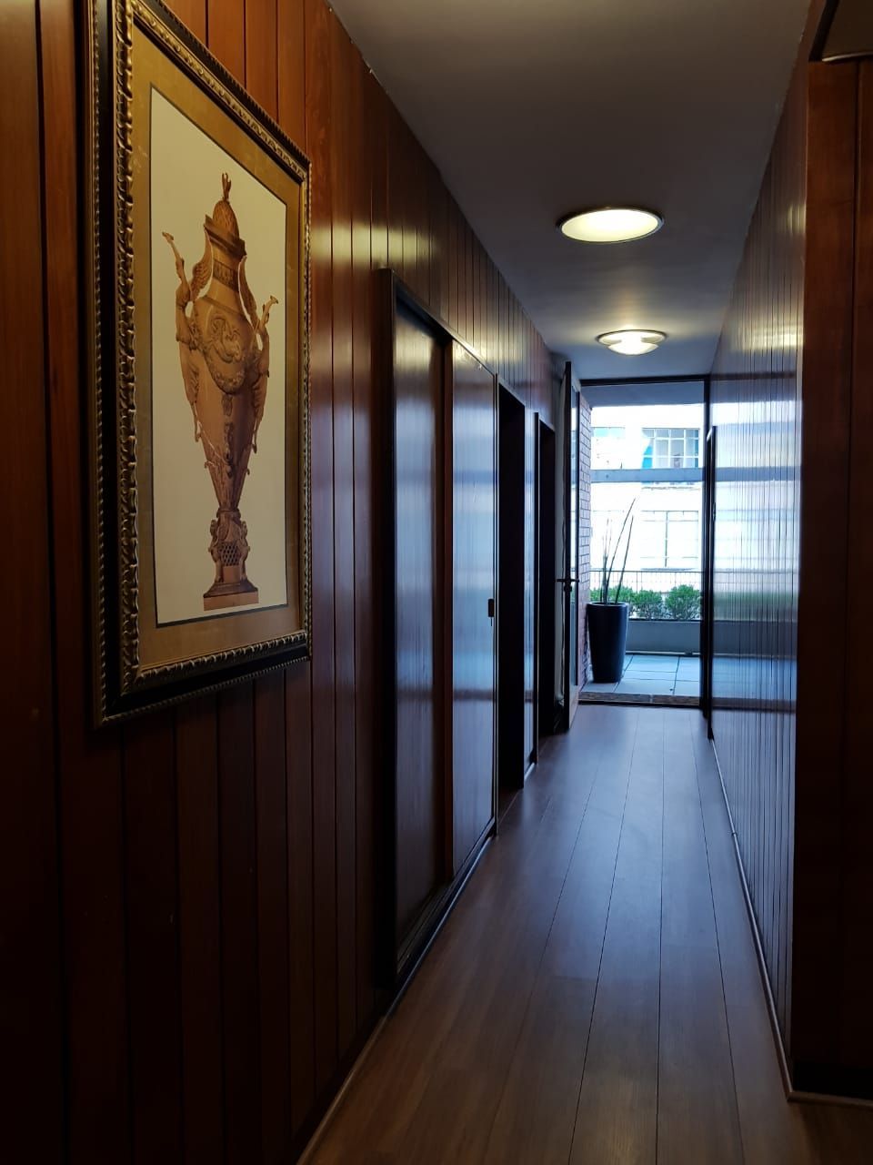 Um corredor com a foto de um vaso na parede