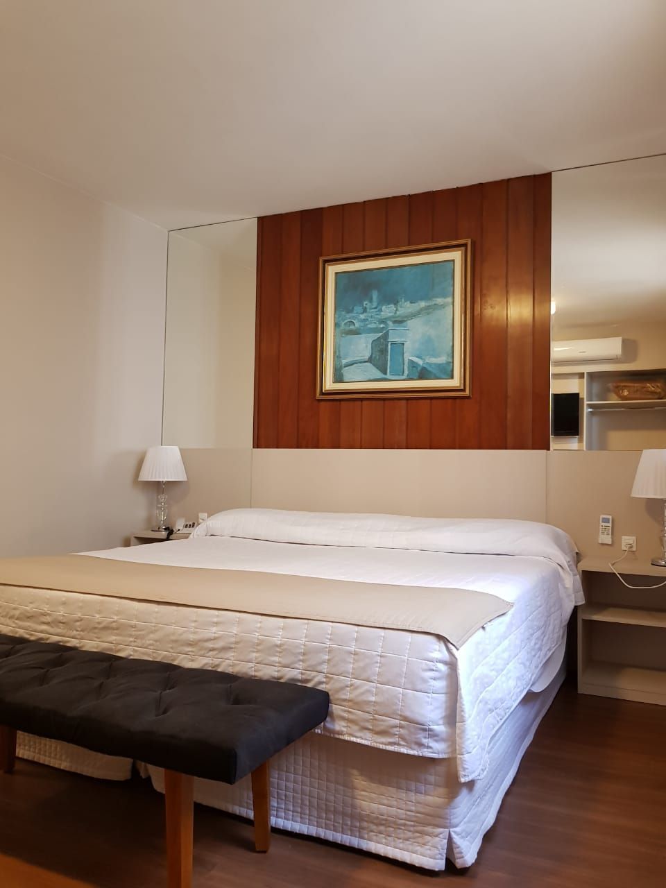 Um quarto de hotel com uma cama grande e uma pintura na parede