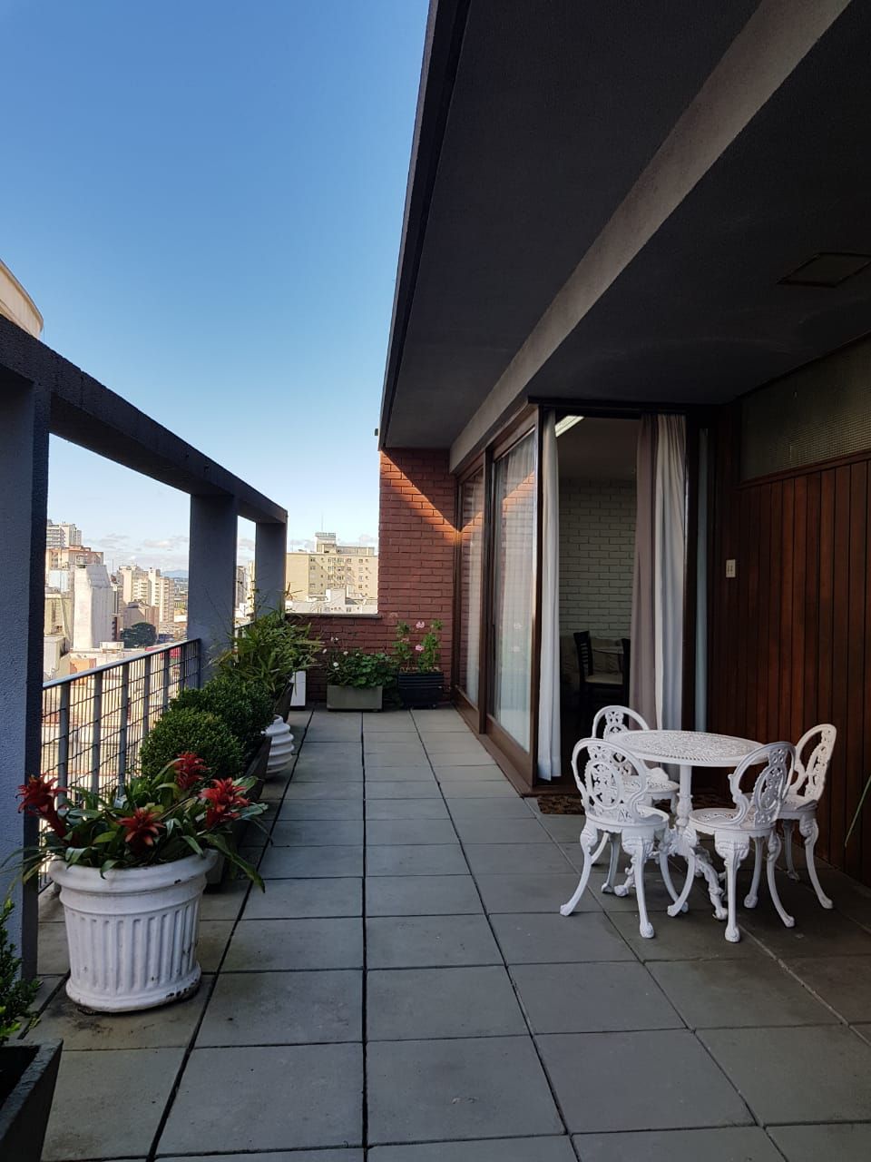 Uma varanda com mesa e cadeiras e vasos de plantas