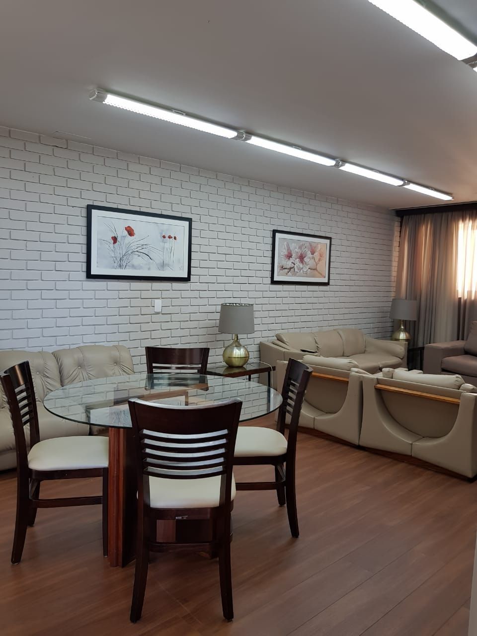 Uma sala de estar com mesa e cadeiras de vidro e parede de tijolos.