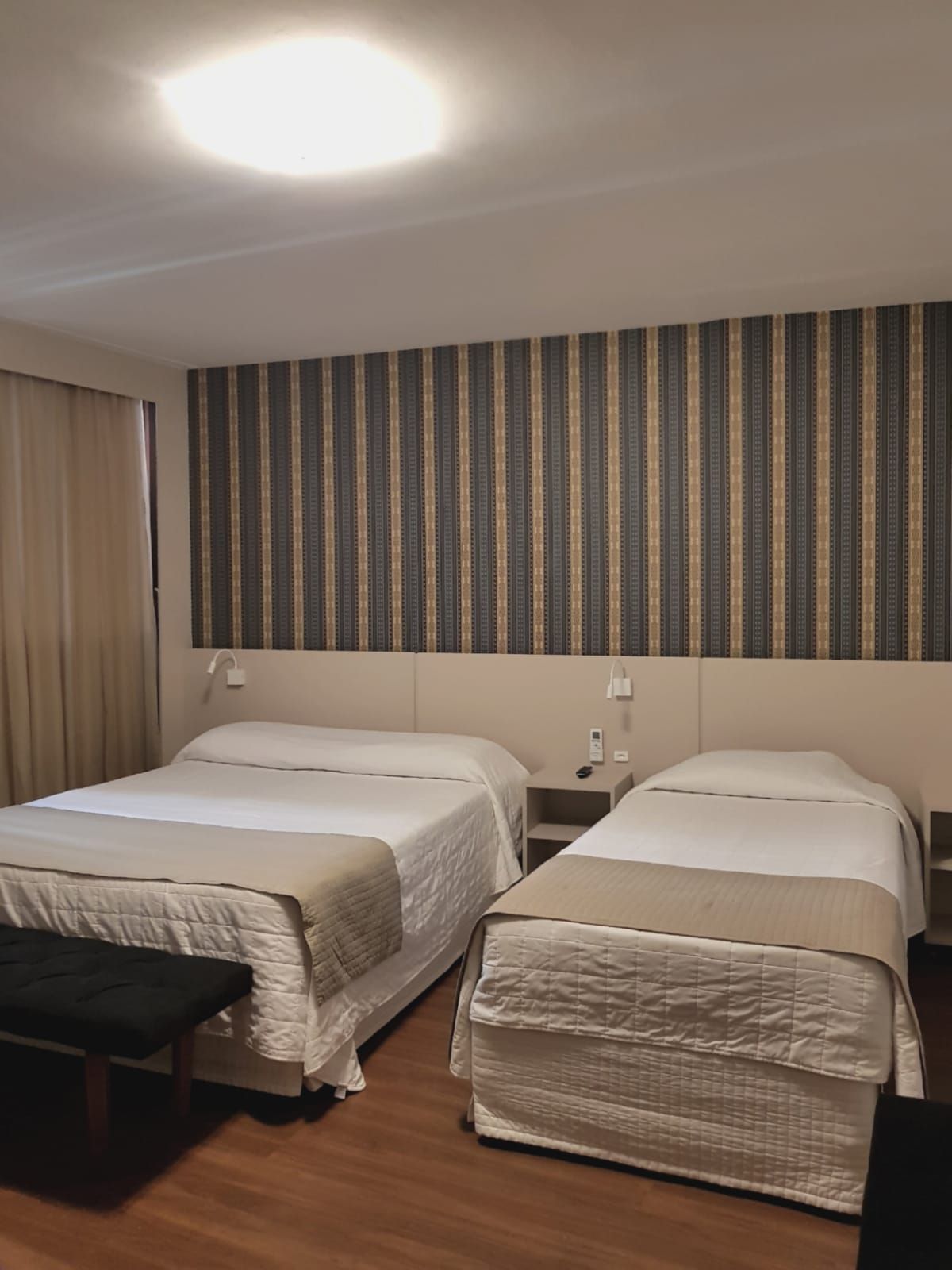 Um quarto de hotel com duas camas e uma parede listrada.