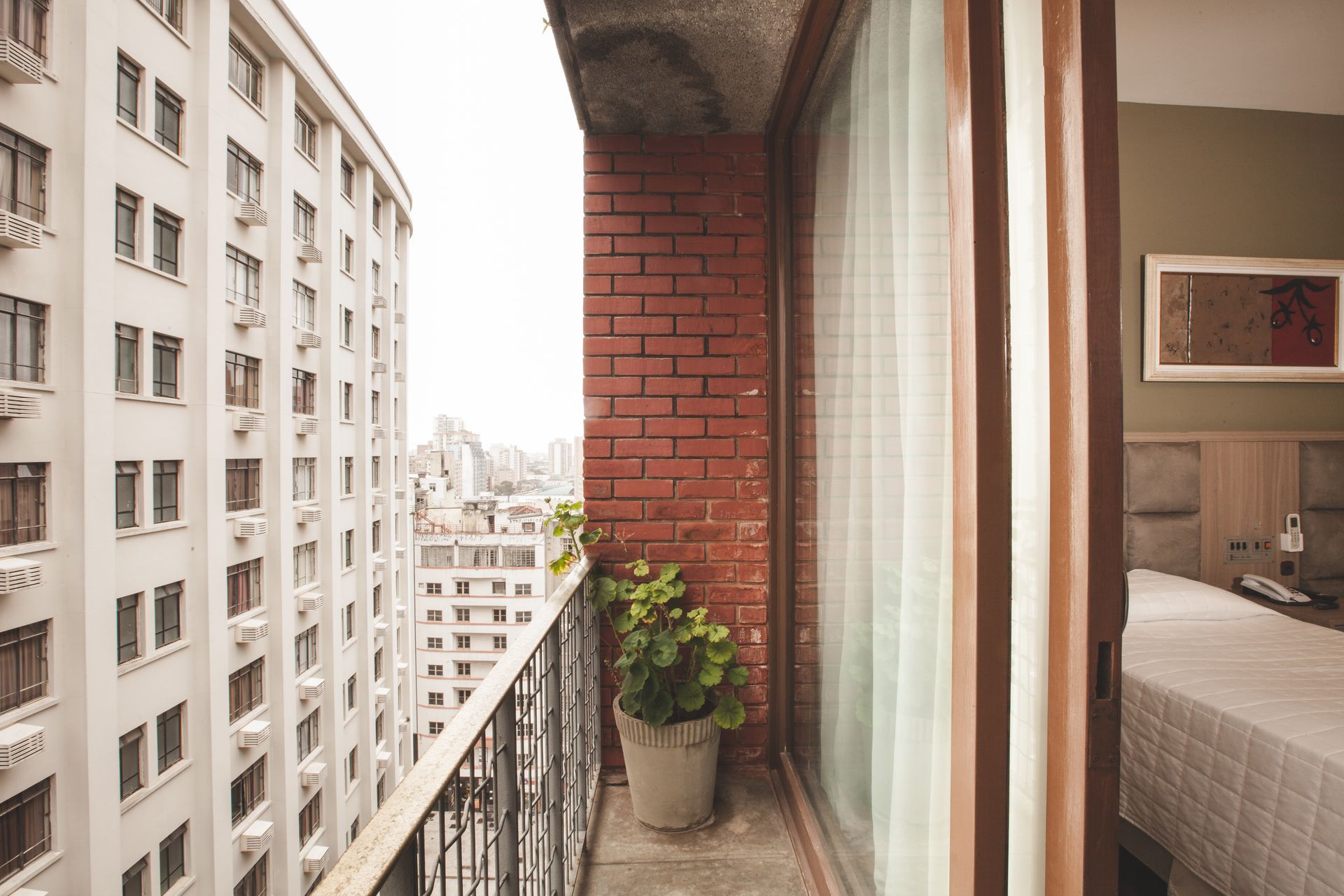 Uma varanda com um vaso de planta e vista para a cidade.